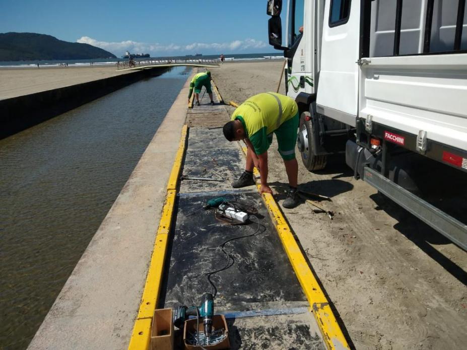 dois homens estão trabalhando na beira do canal 3 para trocar peças da passarela. #paratodosverem 