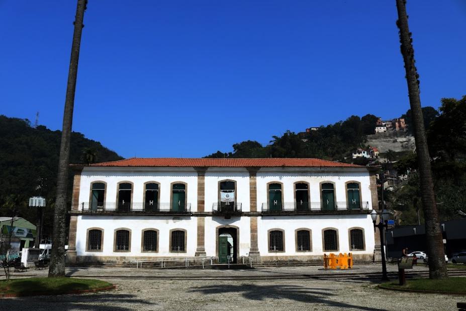 a fachada da cadeia velha, com palmeiras nas duas laterais e em primeiro plano, como se estivessem emoldurando o grande patrimônio. #paratodosverem