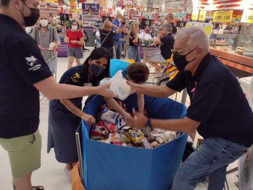 Pessoas mexem em caixa com alimentos no supermercado #paratodosverem