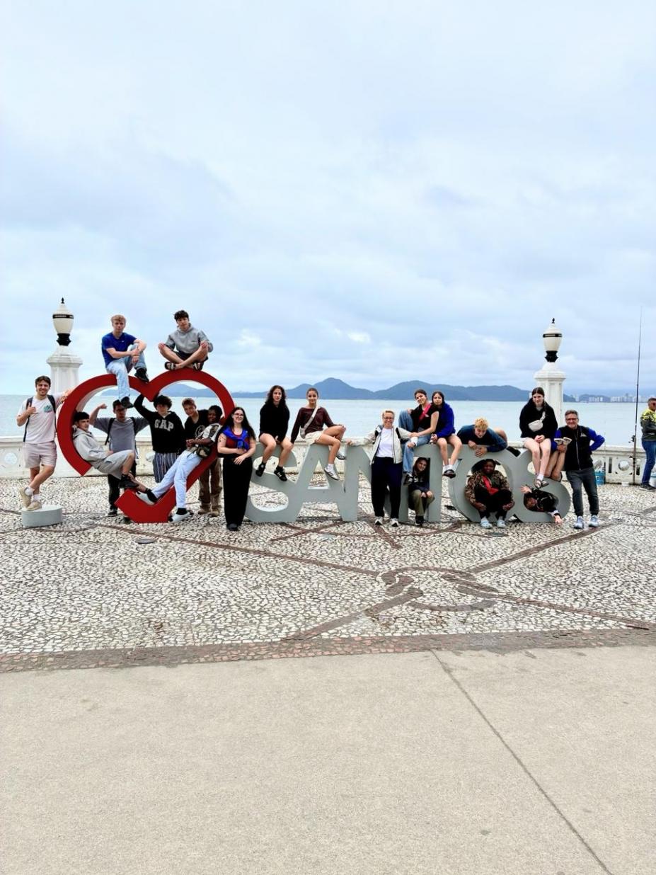 atletas em monumento com o nome da Cidade #paratodosverem