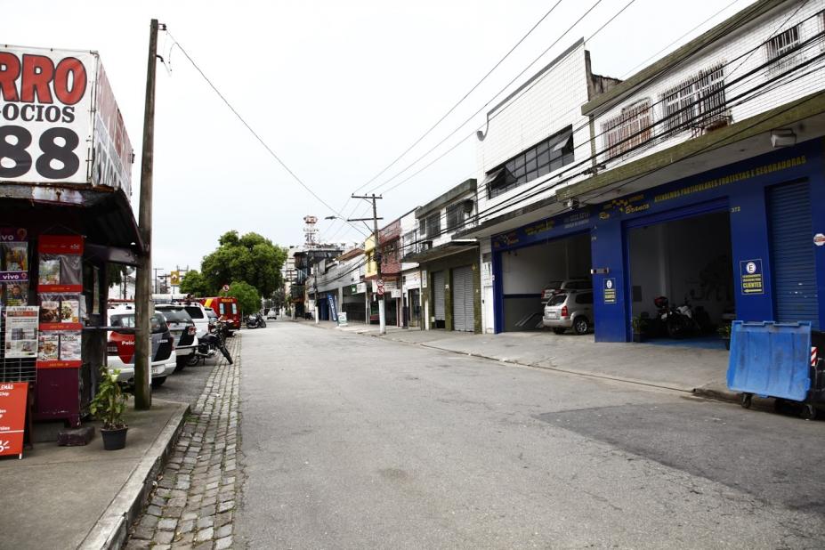 trecho de avenida sem movimento de carros. Ao lado direito há estabelecimentos comerciais; do esquerdo, o canteiro central. #paratodosverem