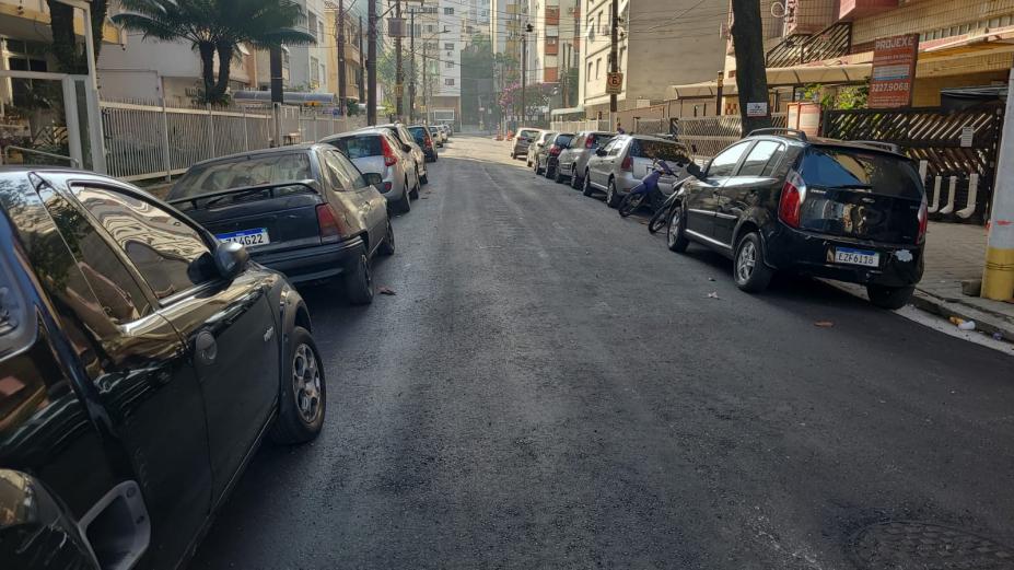 rua recém-asfaltada com carros em ambos os lados. #paratodosverem