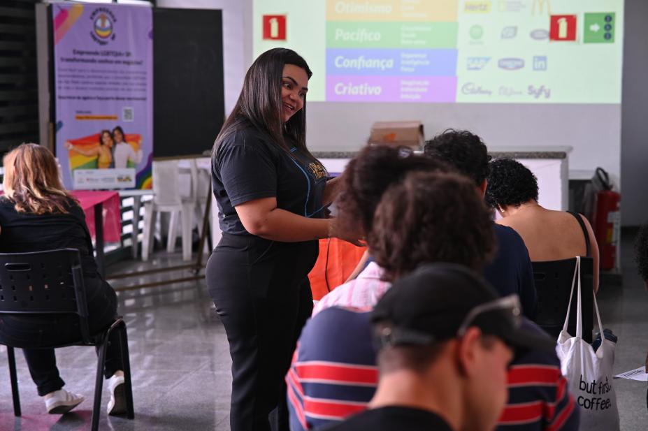 mulher em pé dá aula para pessoas em sala. #paratodosverem