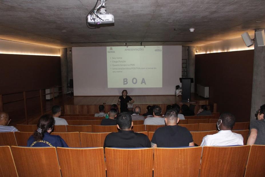 Trabalhadores assistem palestra no auditório do Museu Pelé. #paratodosverem