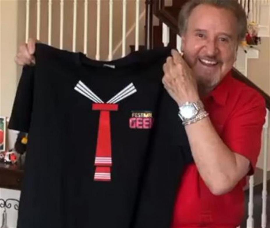 Carlos Villagran, o Kiko, sorri para a foto segurando uma camiseta do seu personagem. #Pracegover