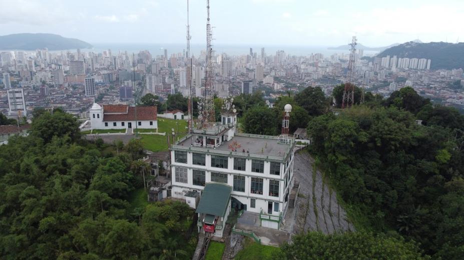 vista aérea geral de morro (o monte serrat), com construção e grande área verde em torno. #paratodosverem