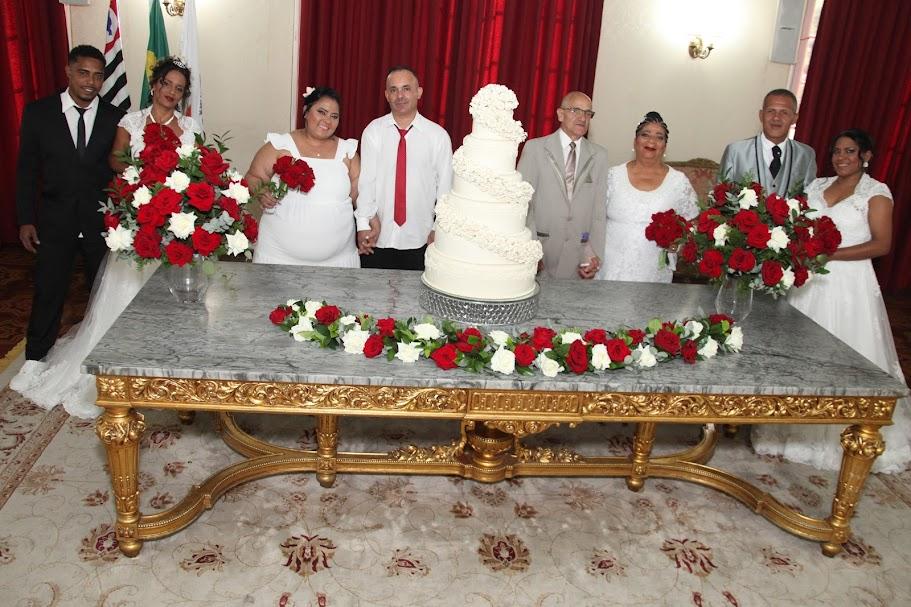 casais de noivos a caráter posam para foto atrás de mesa. #paratodosverem 