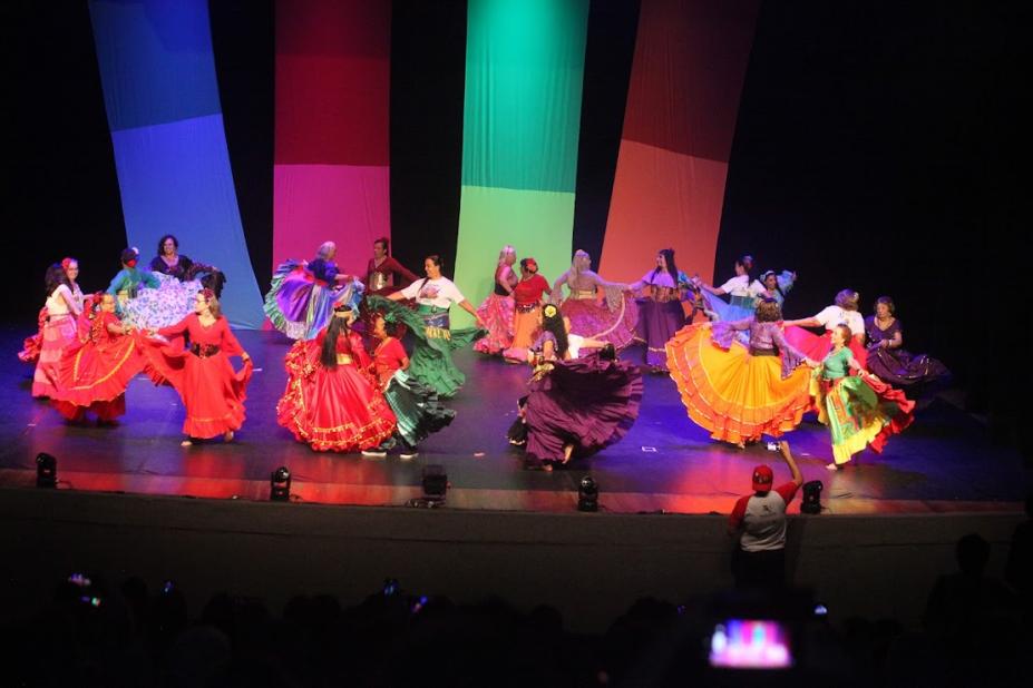 pessoas dançando em palco fantasiadas #paratodosverem