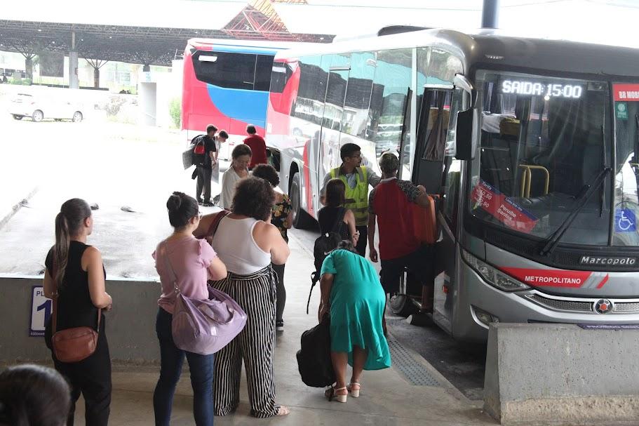pessoas em fila para entrar em ônibus parado em baia de terminal rodoviário. #paratodosverem 