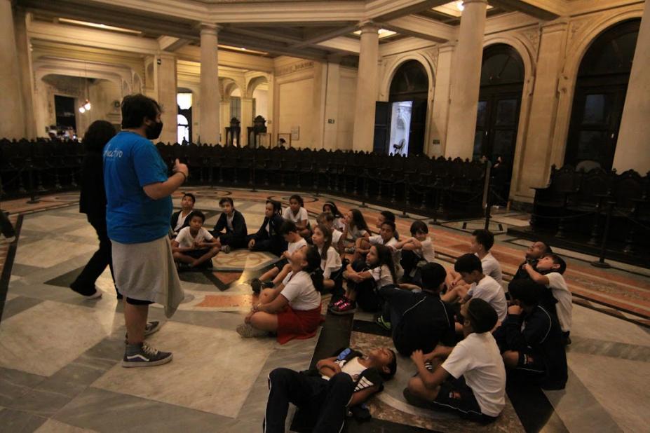 alunos ouvem instrutor sentados no chão da bolsa do café #paratodosverem
