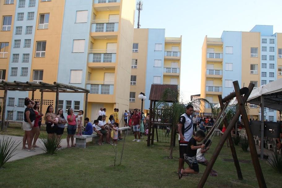 famílias na frente de conjunto habitacional #paratodosverem