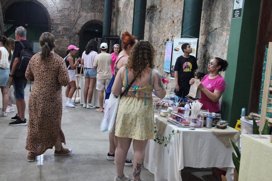 ambiente com exposicão de artesanato e pessoas circulando. #paratodosverem