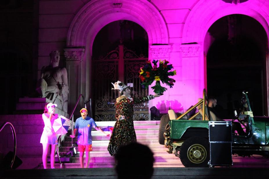 personagens se apresentam na frente de um palácio iluminado #paratodosverem