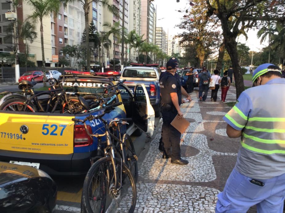 Carro com várias bicicletas em cima e ao lado agente da CET. #paratodosverem