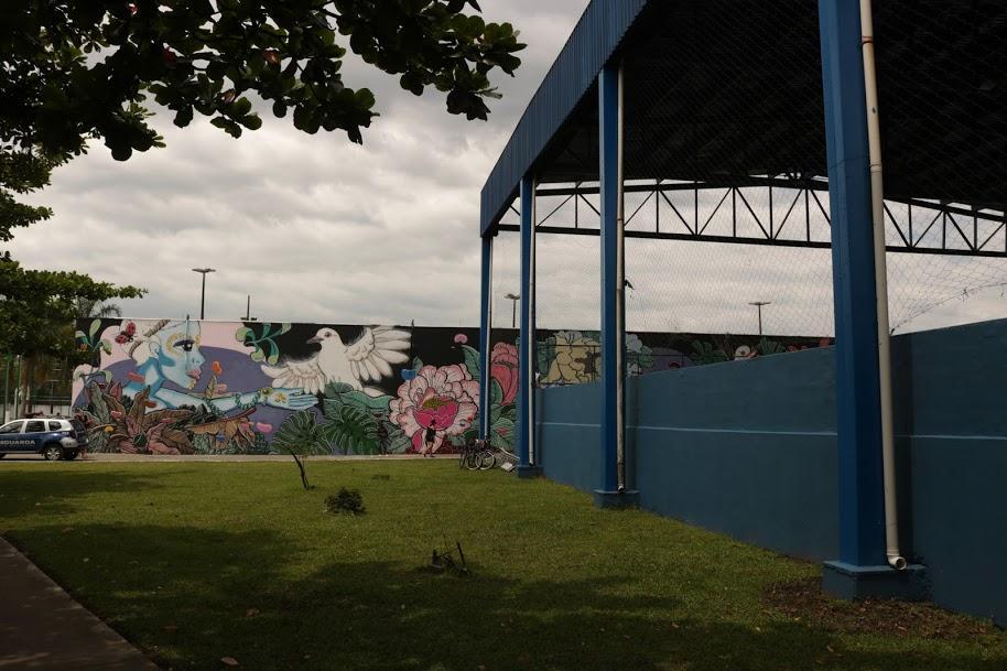 Fachada do CEU das Artes com mural grafitado e parte de cobertura de quadra poliesportiva. #pracegover