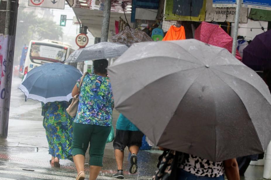 pessoas andando na rua em dia de chuva usando guarda-chuva. #paratodosverem