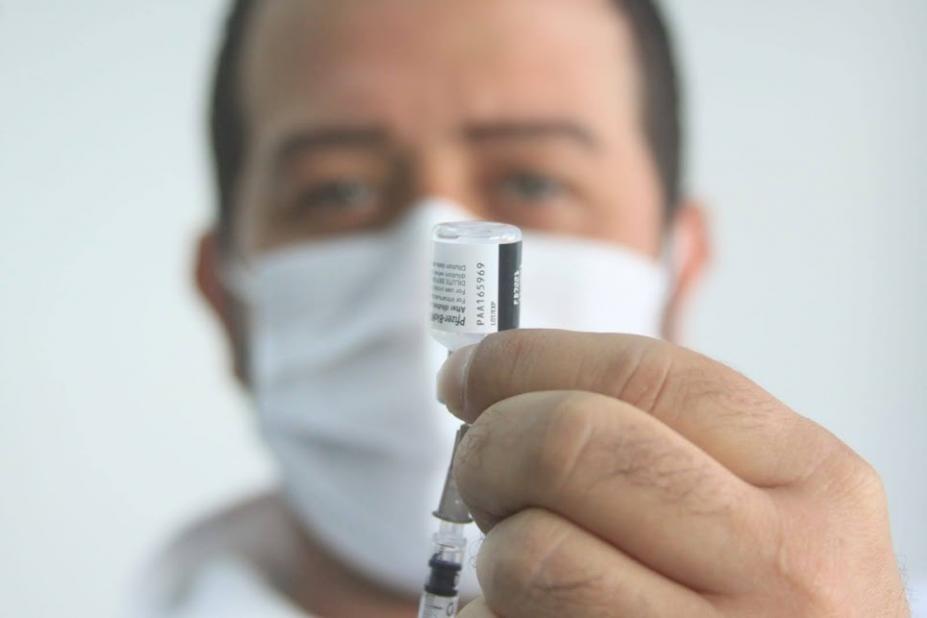 close de frasco de vacinação na mão de homem que usa máscara. #paratodosverem