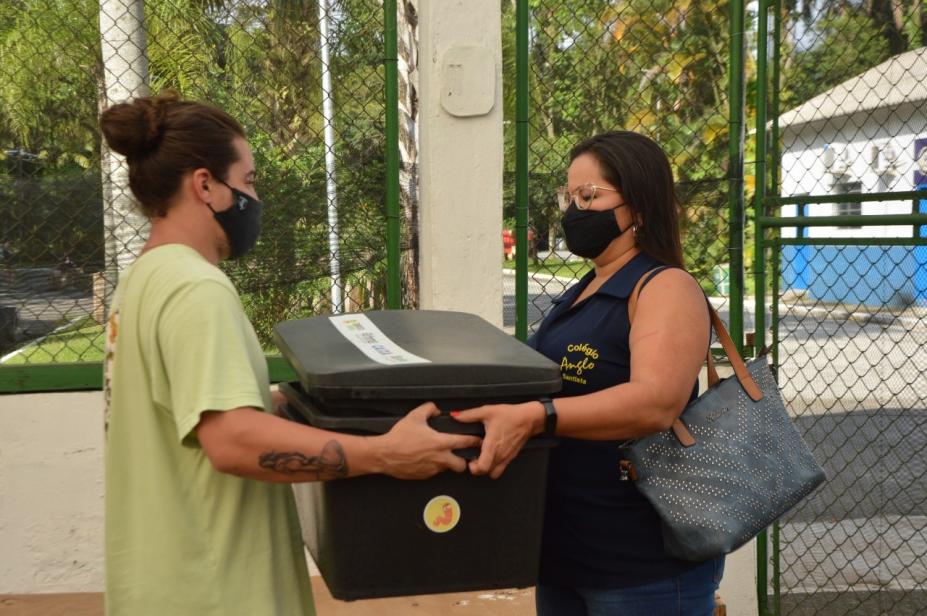 Profissional entrega composteira para mulher representante de instituição. #pracegover