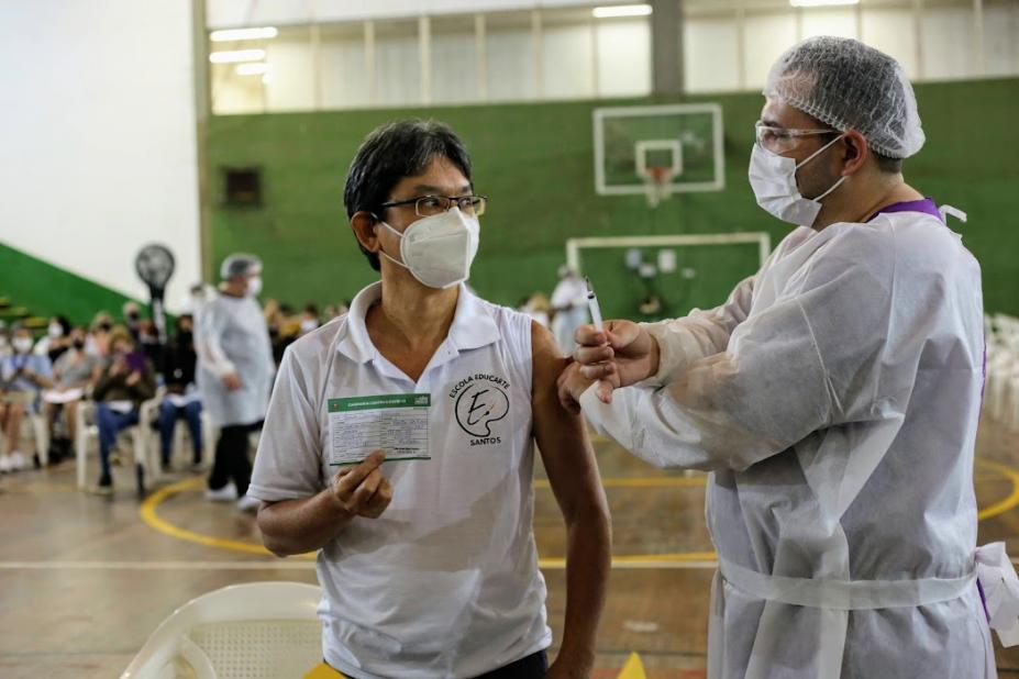 homem é vacinado e segura cartão #paratodosverem