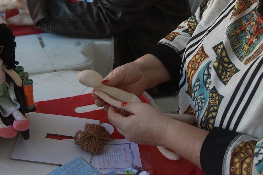 mãos costuram boneca de tecido. #paratodosverem