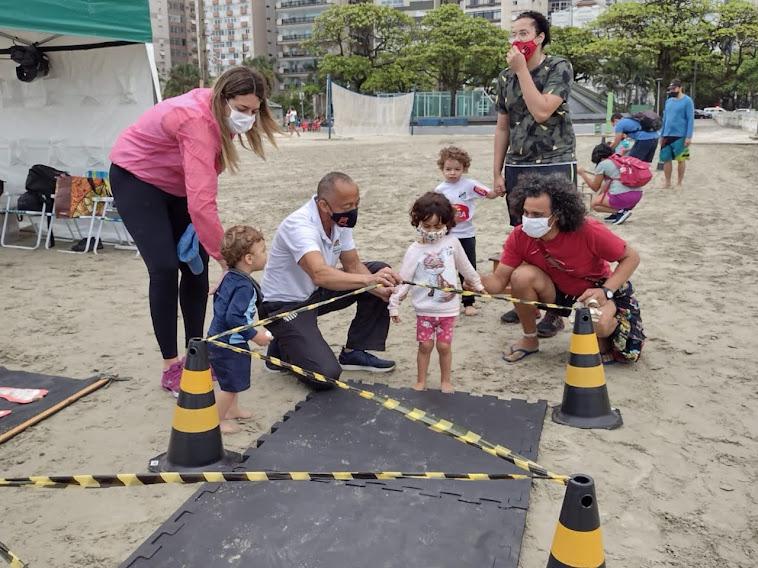 Crianças realizam atividades de lazer na areia da praia #paratodosverem