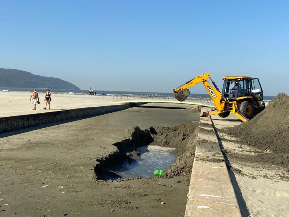 Retroescavadeira retira areia de canal no trecho de praia. #pracegover