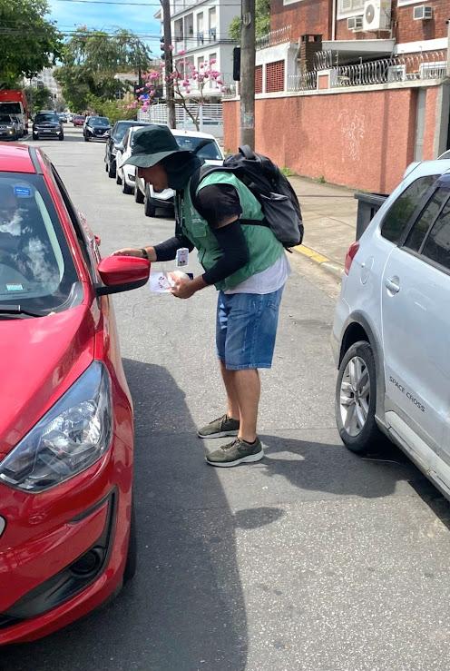agente entrega panfleto a pessoa em carro #paratodosverem