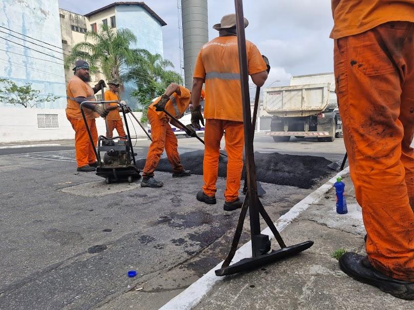 homens cobrem trecho de rua com asfalto. #paratodosverem 