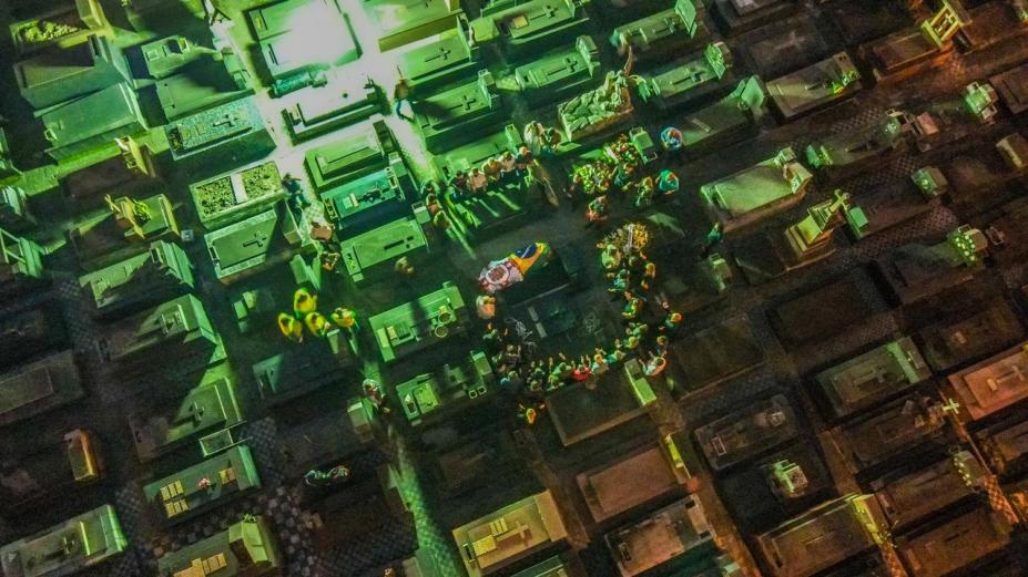 vista aérea do cemitério do paqueta, com féretro ao centro coberto por bandeira do Brasil e da cidade de São Paulo. #paratodosverem