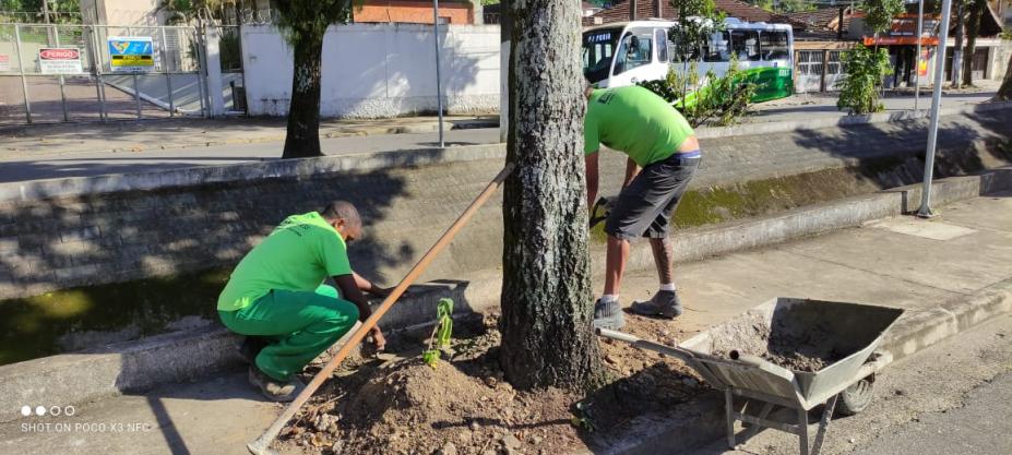 homens uniformizados estão mexendo na terra ao lado de árvores. #paratodosverem