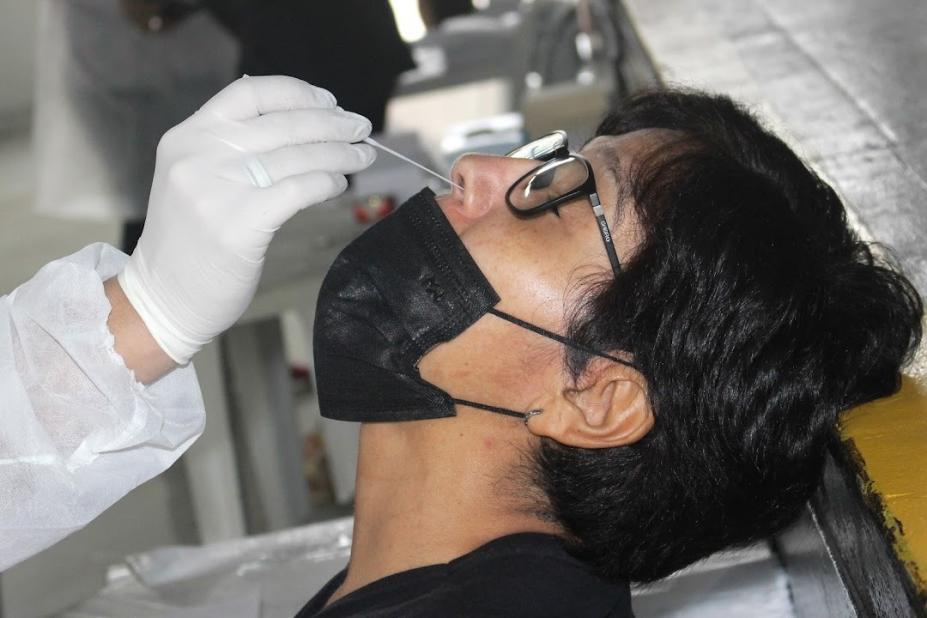 mão introduz 'cotonete' de exame no nariz de uma pessoa. #paratodosverem