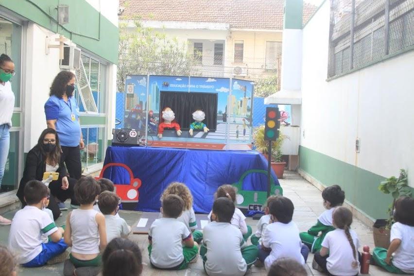 Crianças observam teatro de fantoche sobre trânsito. #paratodosverem