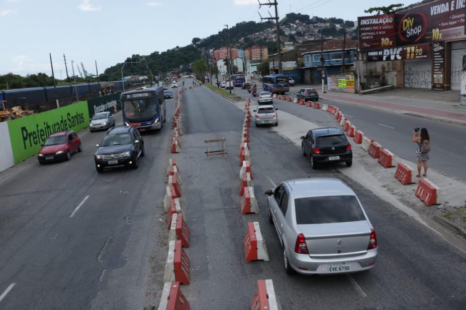 Carros trafegam nos dois sentidos em pistas demarcadas com barreiras plásticas. #pracegover