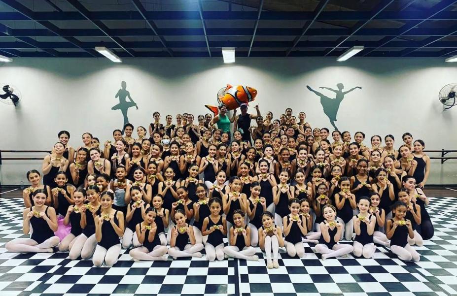 Grande grupo de alunas da escola de bailado posa para foto em sala de dança. #paratodosverem