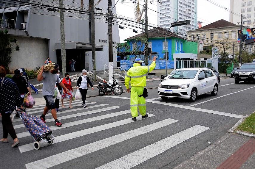 Agente da CET para o trânsito enquanto pedestres atravessam na faixa. #paratodosverem