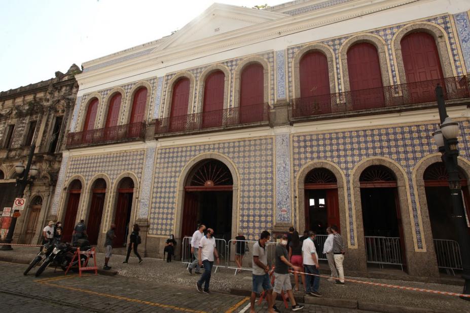 Fachada da casa da frontaria azulejada com pessoas na entrada. Barreiras e faixas limitam a entrada de visitantes por vez. #paratodosverem