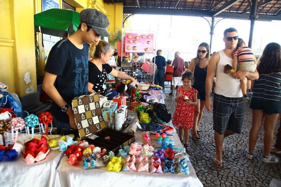 pessoas circulam diante de bancas de artesanato montadas na estação do valongo em Santos. #paratodosverem