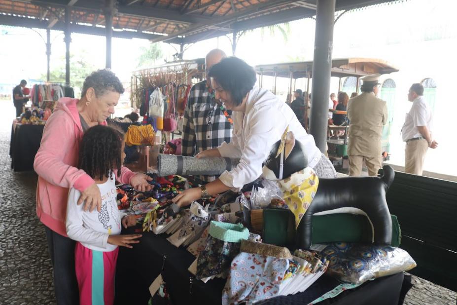 pessoas olhando produtos em feira #paratodosverem