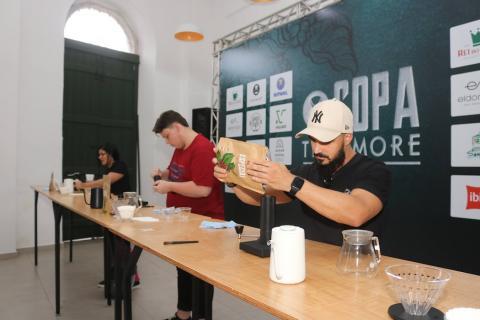 dois homens estão atrás de uma bancada preparando café. #paratodosverem 