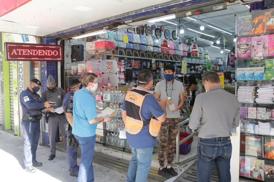 Fiscais, PM e Guarda Municipal em frente a uma loja aberta. #Paratodosverem
