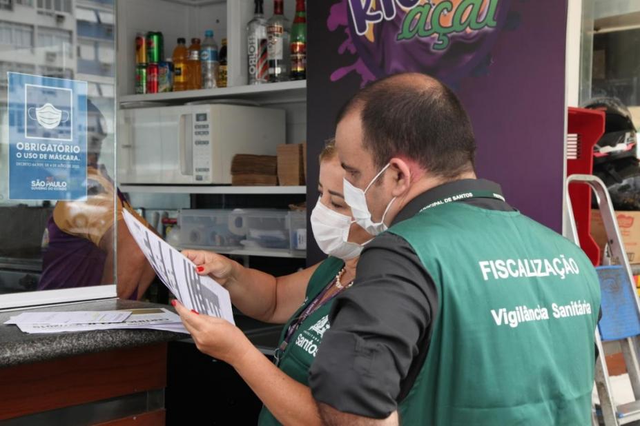 Fiscais observam documentação de comércio. #pracegover