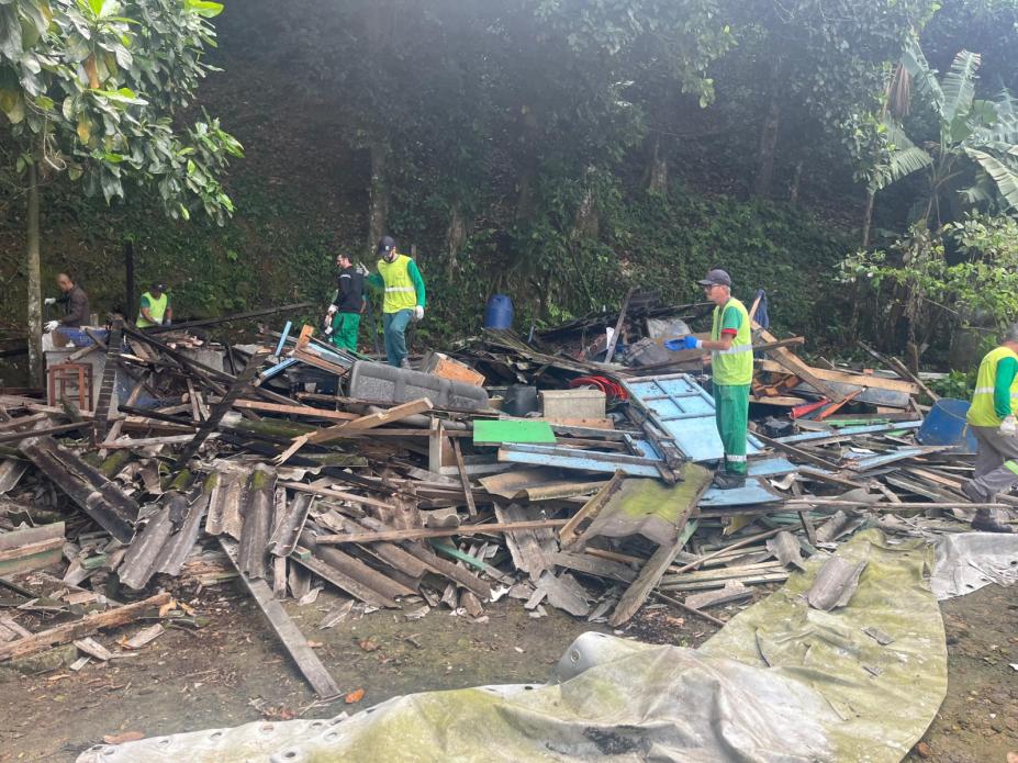 casa derrubada com pessoas na frente