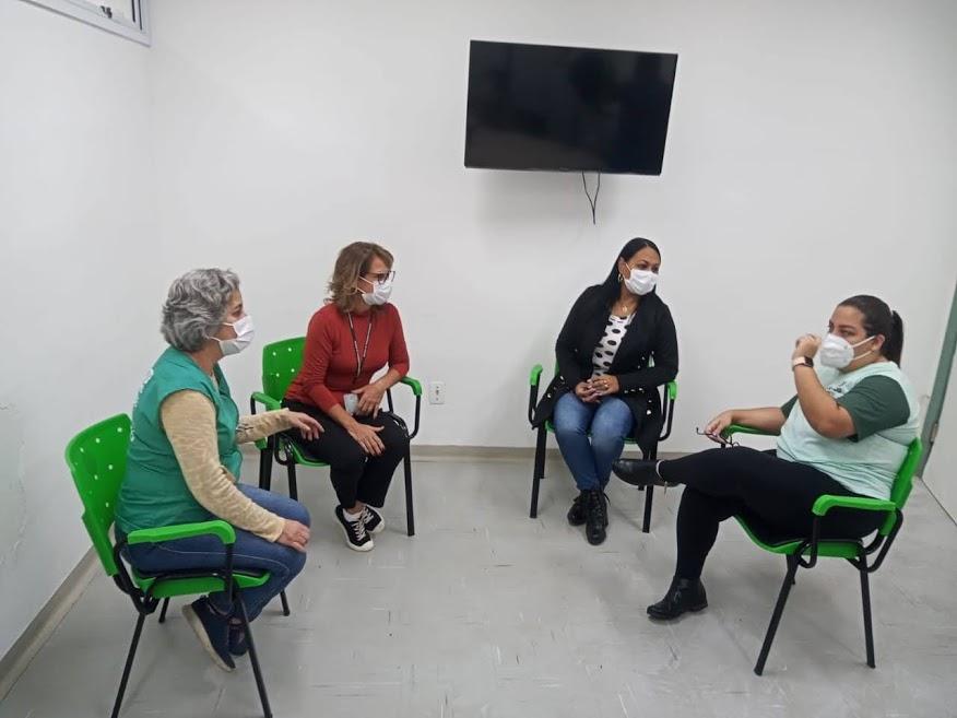 Quatro mulher conversam em uma sala sentadas em cadeiras. #paratodosverem