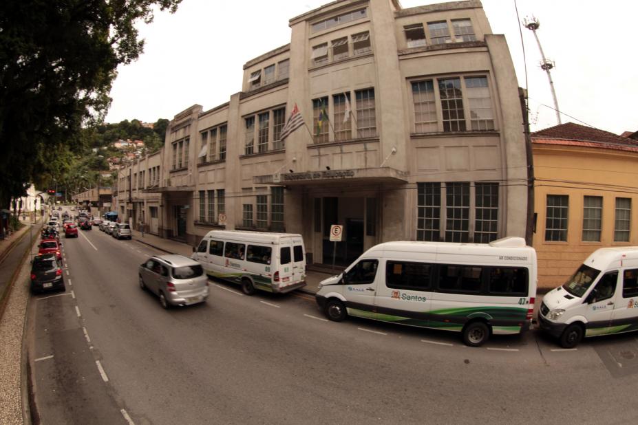 Fachada do prédio da Seduc, com vans de transporte passando à frente. #Pracegover