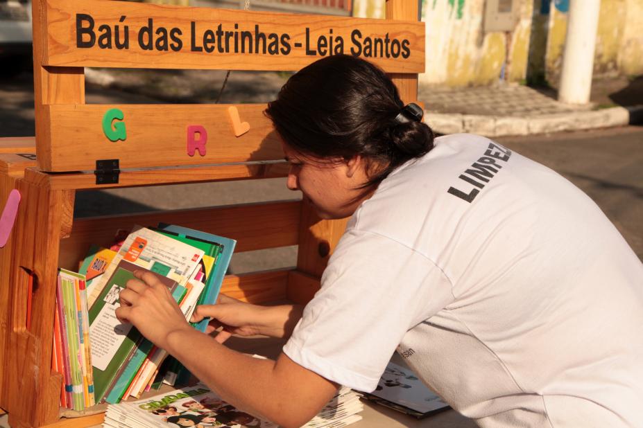 mulher pega  livros em estande do projeto #pracegover 