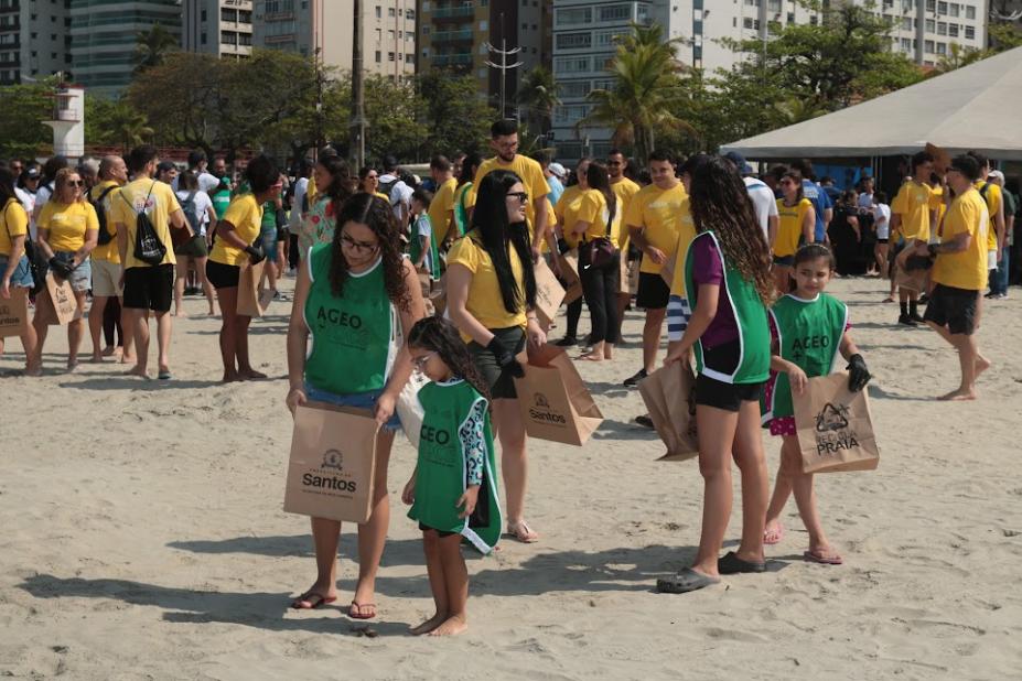pessoas recolhendo lixo em praia #paratodosverem