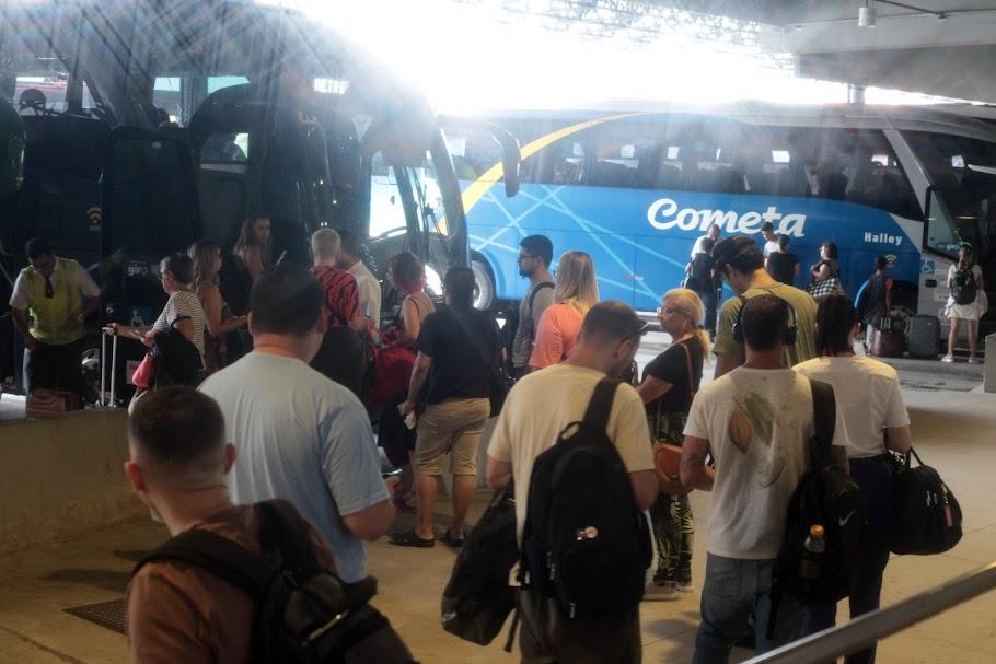 pessoas fazem fila para entrar em ônibus encostadas nas baias da rodoviária. #paratodosverem 