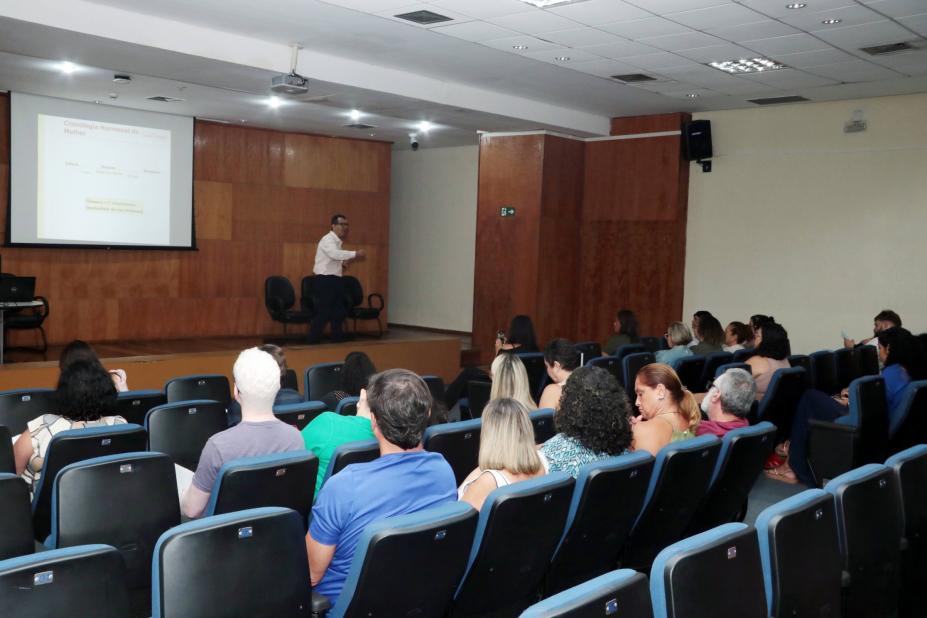 homem está em palco dando palestra em auditório. #paratodosverem 