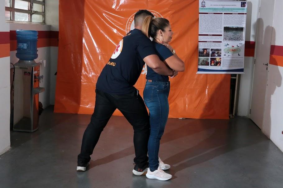 homem abraça mulher por trás e aperta o abdômem dela. #paratodosverem 