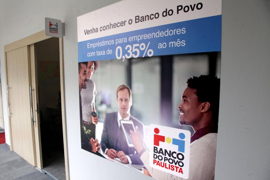 Painel do  Banco do Povo afixado em parede. #Pracegover